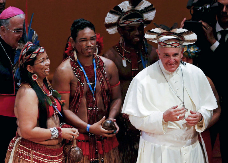 Pope Francis wears an indigenous feathered hat given to him by representatives of one of Brazil's native tribes (AP Photo/Mônica Imbuzeiro, Agência O Globo)