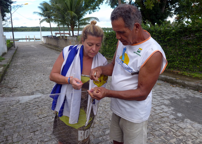 Rosita getting a lesson in fishing net repair from a local on Tinharé Island