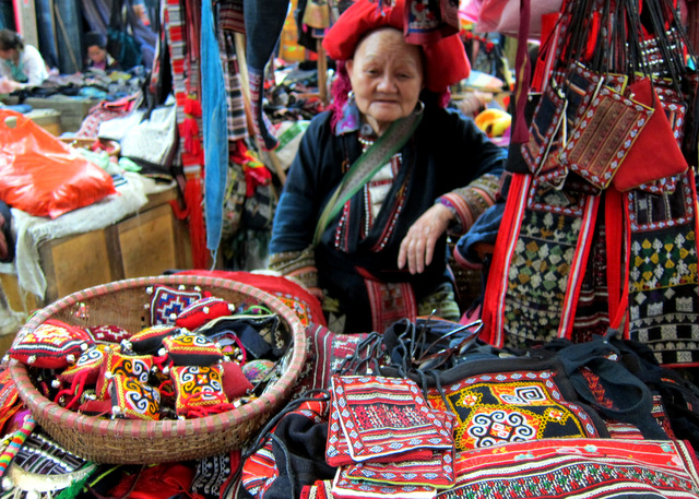 A red Dzao craftswoman in the market, they work busily creating beautiful sewing and needlework textiles
